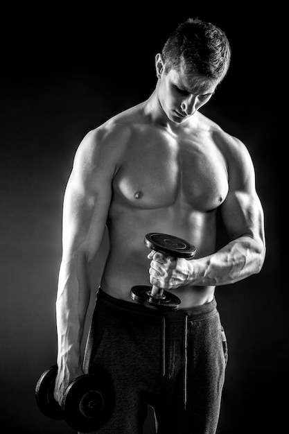 Poderoso homem de fitness mostrando seu corpo gread com halteres