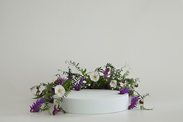 Podio blanco sobre fondo blanco con flores Podio para maqueta de presentación cosmética del producto