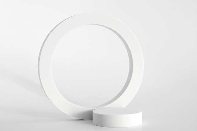 Podio blanco sobre fondo blanco, formas geométricas simples. Podio para producto, presentación cosmética. Maqueta creativa. Pedestal o plataforma para productos de belleza.