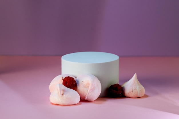 Podio geométrico para demostración de productos Galletas de merengue y frambuesa sobre fondo rosa