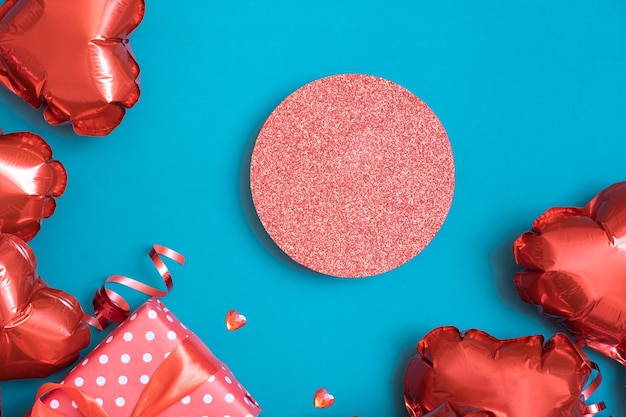 Podio o pedestal y caja de regalo con globos en forma de corazón rojo sobre fondo turquesa Plantilla del Día de San Valentín