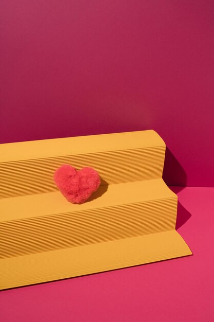 Foto podio de papel amarillo con corazón de felpa rosa sobre fondo magenta concepto mínimo