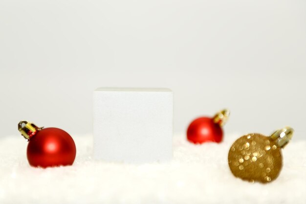 Pódio quadrado branco com bolas de Natal vermelhas na neve branca