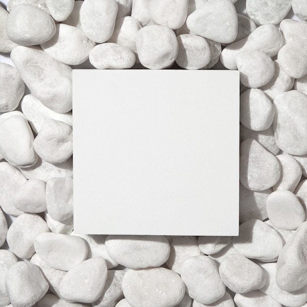 Pódio quadrado branco sobre fundo de pedra de seixos brancos. Camada plana, vista superior.