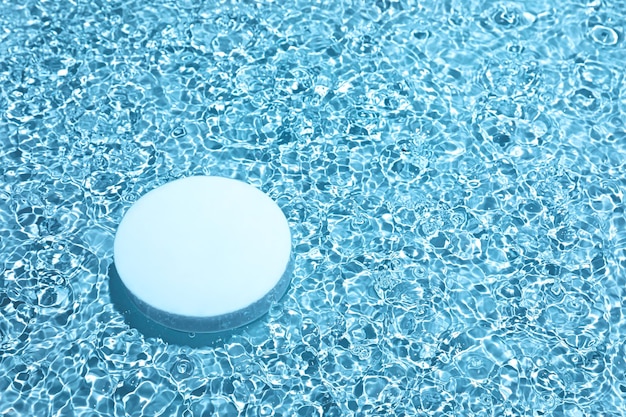 Foto podium de círculo blanco vacío sobre fondo de agua azul transparente con espacio para copiar