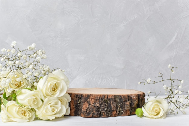 Podium für Produktpräsentation. Eine minimalistische Szene eines gefällten Baums mit weißen Rosen auf grauem Hintergrund. Vitrine für die Ausstellung. Platz kopieren. Flache Lage, Draufsicht.