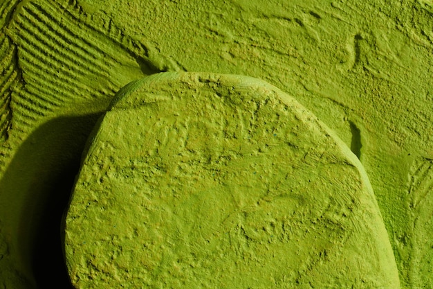 Podiumsdisplay aus grünem Stein auf grünem Hintergrund. Dekorativer strukturierter Ständer für Schönheitsprodukte mit KopierraumxA