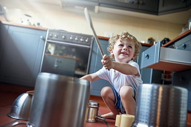 Podrías llamarlo ruido, pero los niños lo llaman diversión Foto de un adorable niño pequeño tocando la batería en un juego de ollas en la cocina