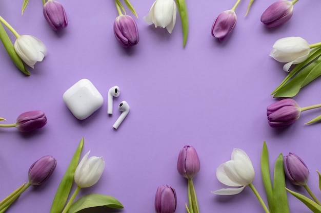 Pods de fones de ouvido sem fio e tulipas de primavera em fundo violeta
