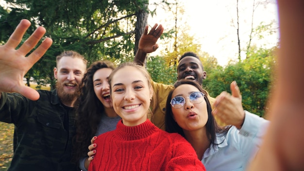 Point-of-View-Aufnahme von fröhlichen Männern und Frauen, die Freunde aus dem Park anrufen und online anrufen, in die Kamera schauen, reden und lachen, draußen stehen und Spaß haben