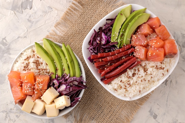 Poke bowl comida hawaiana. un plato con arroz, salmón, aguacate, repollo y queso sobre un fondo claro.