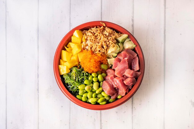 Foto poke bowl grande de atún rojo picado con mango masago huevas de edamame alga wakame aguacate arroz blanco y cebolla crujiente