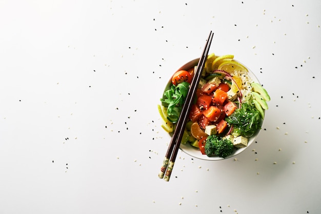 Poke Bowl mit Lachs, Avocado, Gurke, Rucola, Broccoli, Karotten mit Chukasalat, Essstäbchen