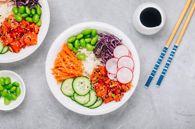 Poke bowl de salmón con arroz, rábano, pepino, zanahorias, edamame, repollo rojo y semillas de sésamo Vista superior