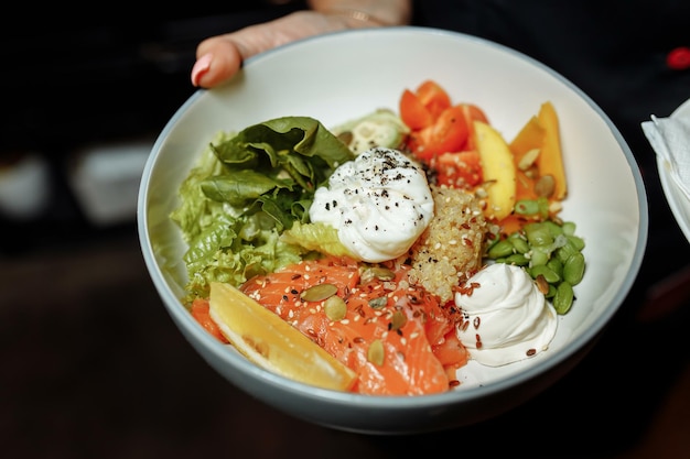 Poke bowl con salmón, espinacas, quinoa, pepino y rábano. Concepto de alimentación limpia.