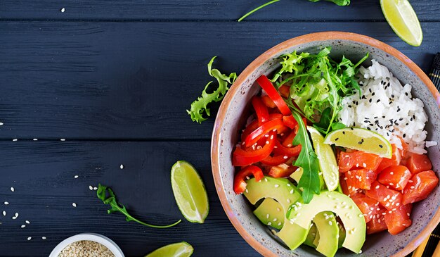 Poke bowl de salmón hawaiano con arroz, aguacate, pimentón, semillas de sésamo y lima. Tazón de Buda. Comida dietetica. Vista superior