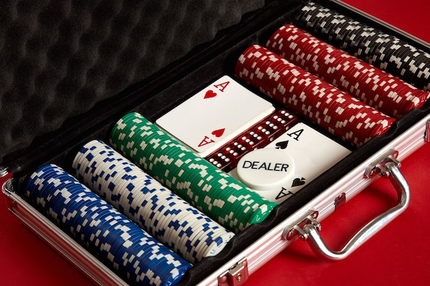 Poker en maleta de metal arriesgado entretenimiento de juegos de azar vista superior sobre fondo rojo.