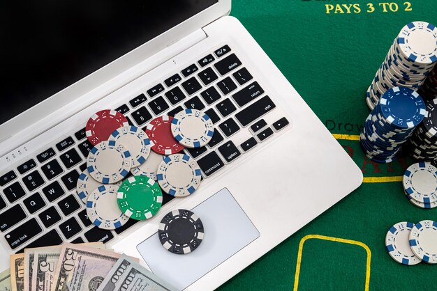 Pokerchips mit Banknoten auf einer Laptoptastatur. Pokerkonzept