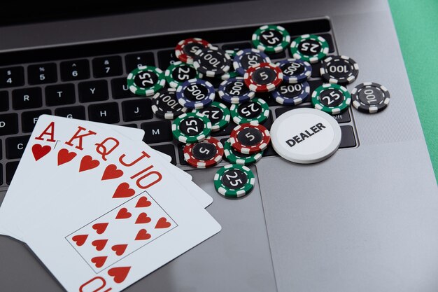 Pokerkarten und Stapel von Pokerchips auf einem Laptop. Poker Online-Konzept.