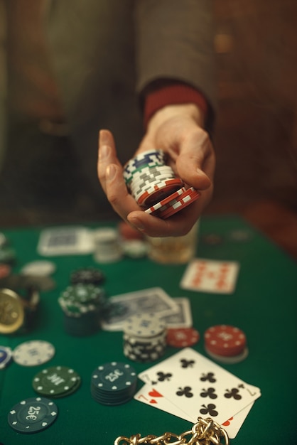 Pokerkonzept, Geldwette, Karten und Chips am Spieltisch, Whisky und Zigarre im Casino.