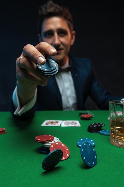 Pokerspieler wirft Chips auf den grünen Tisch im Casino.