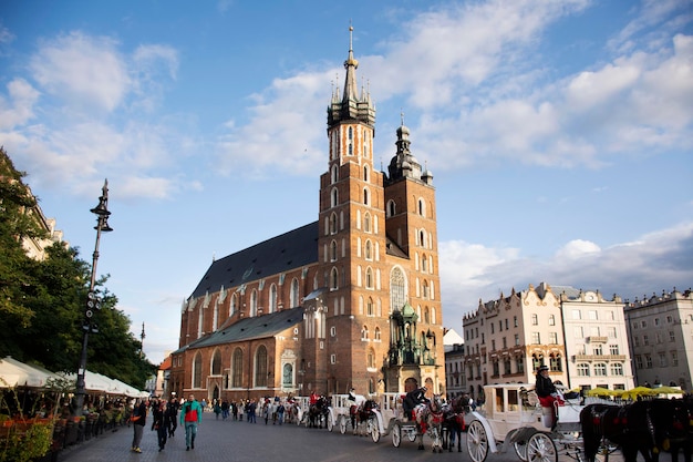 Los polacos esperan y montan carruajes tirados por caballos para los polacos y los viajeros extranjeros que utilizan el servicio de recorrido por el casco antiguo de Cracovia en la plaza del mercado principal en Stare Miasto el 20 de septiembre de 2019 en la Pequeña Polonia