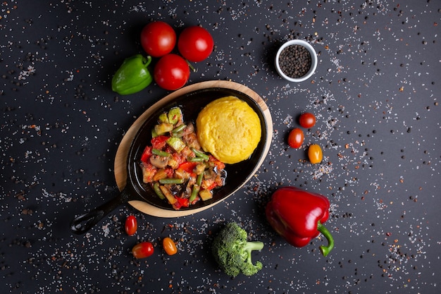 Polenta com guisado, em preto, com tomate, pimentão vermelho e brócolis