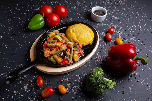 Polenta com guisado, em preto, com tomate, pimentão vermelho e brócolis