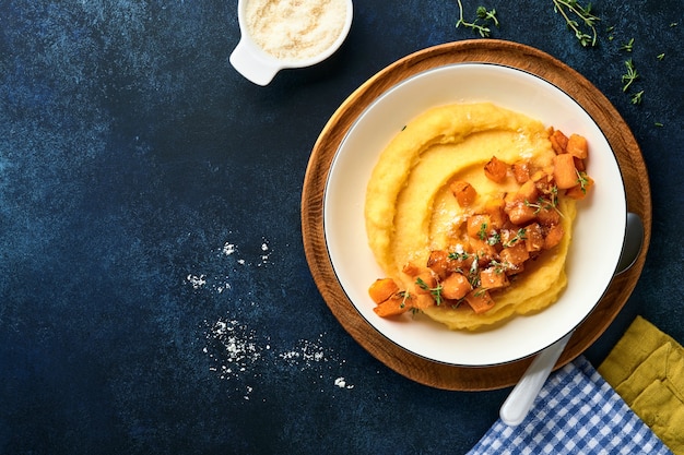 polenta com manteiga, abóbora, alho, queijo parmesão e salgado em uma tigela branca sobre azul