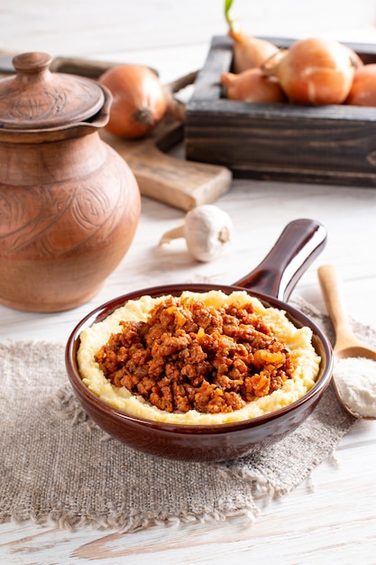 Polenta com molho à bolonhesa fresco em um prato sobre uma mesa de madeira