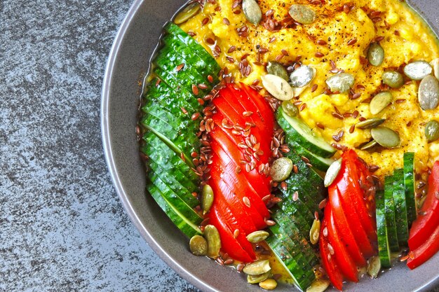 Polenta con verduras. Gachas de maíz con verduras. Almuerzo vegano con gachas de maíz. Comida vegana de polenta, verduras, semillas de lino y semillas de calabaza.