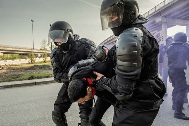 Policial de choque habilidoso com capacetes, segurando o rebelde pelas costas enquanto prendia pessoas em um comício