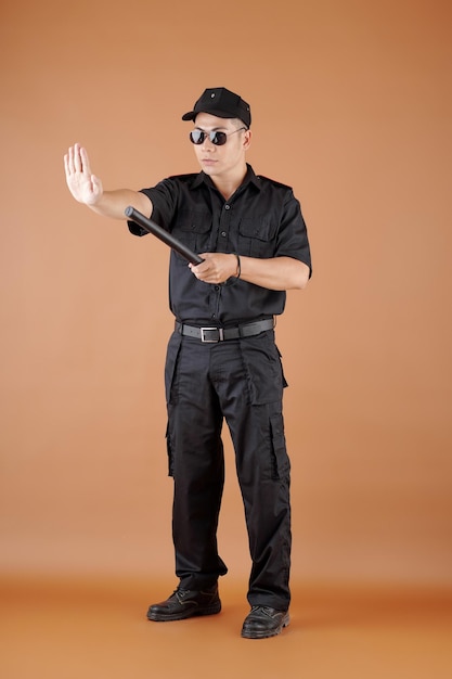 Policial sério e confiante com bastão de borracha fazendo gesto de parada