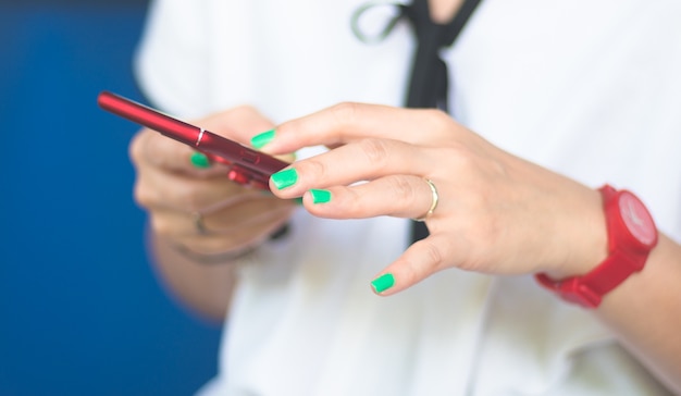 polierte Frau des grünen Nagels, die roten Smartphone verwendet