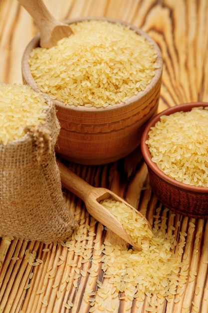 Polierter gedämpfter Reis in Schalen und Beuteln auf Holzhintergrund Hochwertiges Foto
