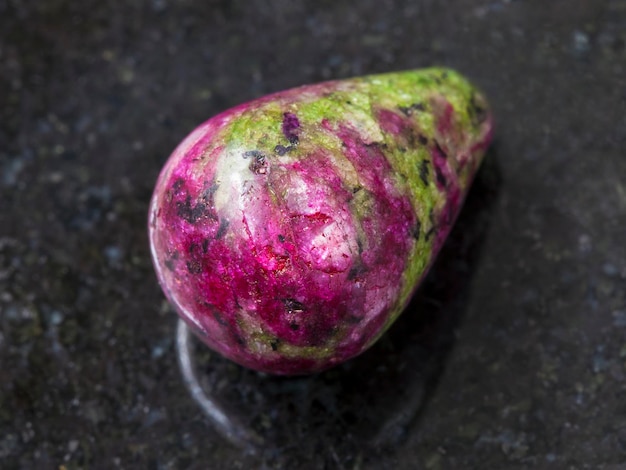 Polierter rosa und grüner Zoisit-Edelstein auf dunkel