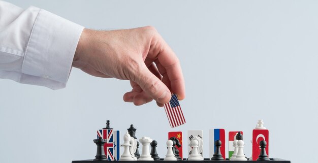 Politiker Hand bewegt eine Schachfigur mit einer Flagge Konzeptfoto eines politischen Spiels
