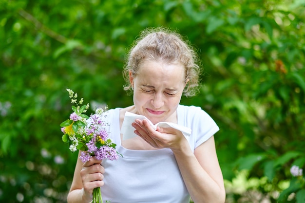 Pollenallergie, Mädchen, das mit Blumenstrauß von Blumen niest. Konzept: saisonale Allergie.