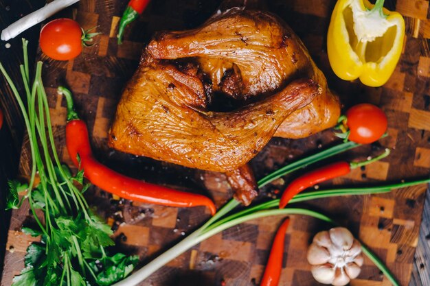 pollo ahumado pollo horneado en un ahumadero en una tabla de cortar decorada con verduras