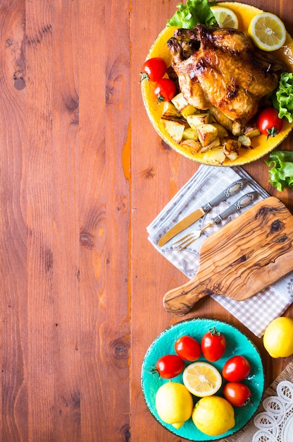 Pollo al horno casero con limón y papas en una mesa de madera