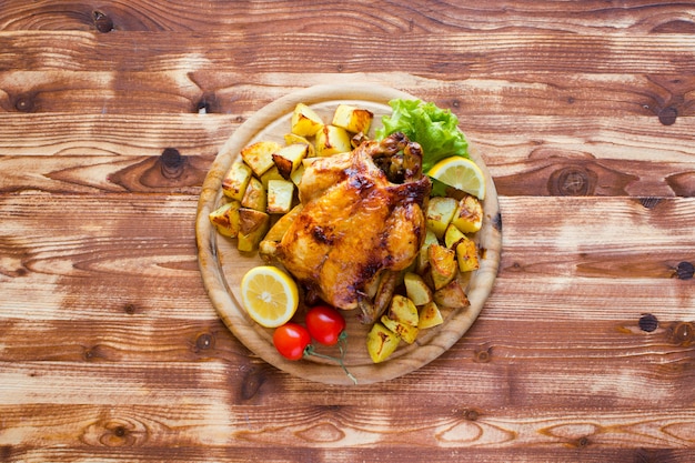 Pollo al horno casero con limón y papas sobre un fondo de madera