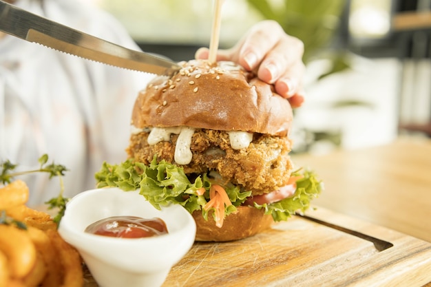 Pollo al horno sabroso con salsa de rúcula y mayonesa servido en una tabla de madera, hamburguesa de pollo con queso y papas fritas rizadas condimentadas picantes