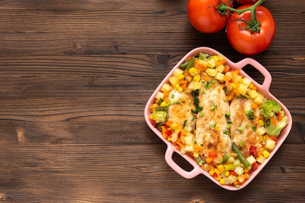 Pollo al horno con verduras sobre un fondo de madera