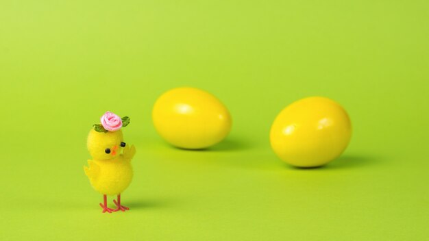 Un pollo amarillo con una flor en el fondo de dos huevos amarillos.