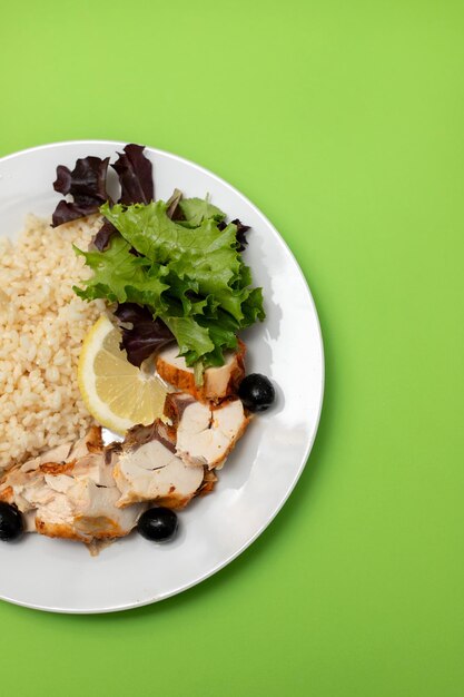 Pollo con arroz hervido y ensalada en plato blanco