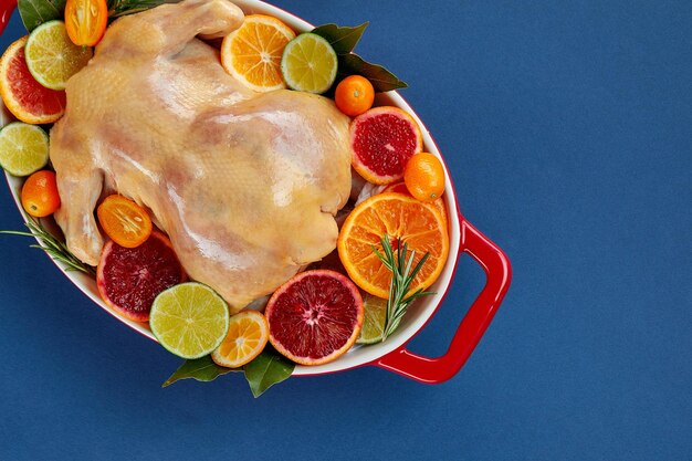 Pollo asado al horno con hierbas y cítricos Pollo entero en una lata para asar con limón y hierbas listo para el horno Vista superior espacio en blanco