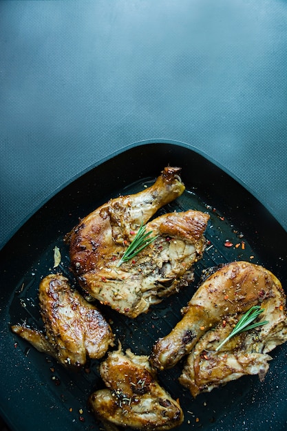 Pollo asado en una cacerola de la parrilla en un fondo oscuro.