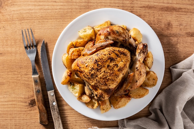 Pollo asado casero con patatas en mesa de madera