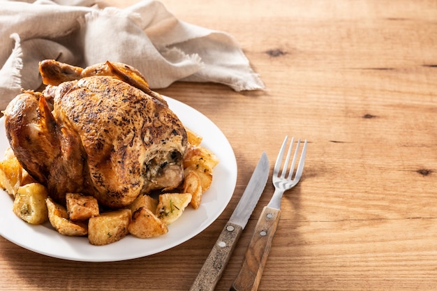 Pollo asado casero con patatas en mesa de madera