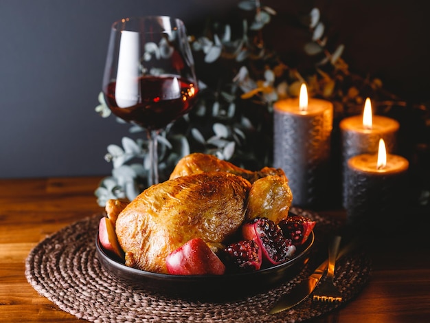 Pollo asado entero con manzana granada y vino tinto en una mesa festiva Concepto de cocina de Navidad o Año Nuevo